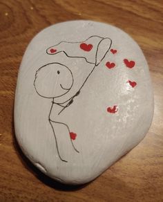 a painted rock with a drawing of a man holding a woman's hand and hearts on it