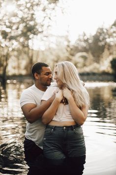 a man and woman standing in the water near each other with their arms around each other