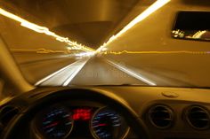 the inside view of a car driving through a tunnel at night with bright lights on it