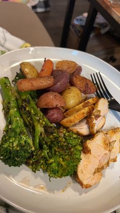 a white plate topped with chicken, potatoes and broccoli next to a fork