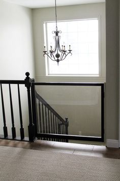 a baby gate for metal spiral staircases in a house with a chandelier hanging from the ceiling