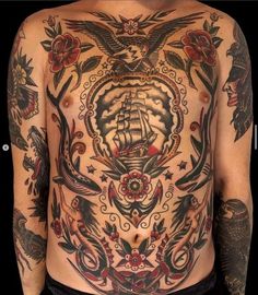 a man's back with tattoos on it and an image of a ship in the middle