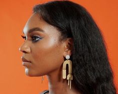 a woman with long black hair wearing large gold earrings on her ear and looking off to the side