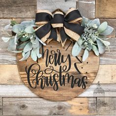 a wooden sign that says merry christmas with succulents and ribbon on it