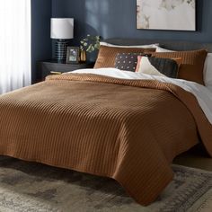 a bed in a bedroom with blue walls and a brown comforter on top of it