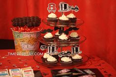 a table topped with cupcakes covered in white frosting and black toppers