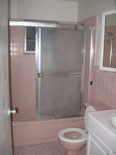 a bathroom with pink tiles and a white toilet next to a walk in shower stall