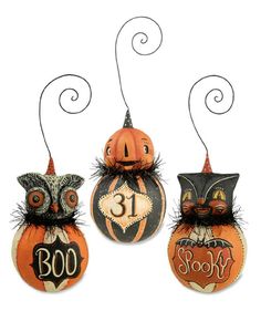 three pumpkins decorated to look like cats and bats with numbers on them, hanging from wire