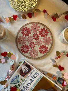 a table topped with plates and cups filled with food next to a book on top of a white cloth