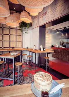 the interior of a restaurant with wooden tables and stools, red carpeting and baskets hanging from the ceiling