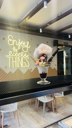 an ice cream sundae is on display in a store window with the words enjoy the little things above it