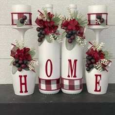 three white vases with red and green decorations are sitting on a mantle next to candles