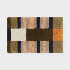 a multicolored rug on a white surface with an orange, brown and black stripe pattern