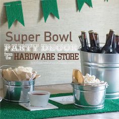 some beer bottles are sitting in buckets on a table with green grass and bunting