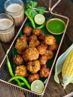 some food is sitting on a tray and next to two glasses with drinks in them