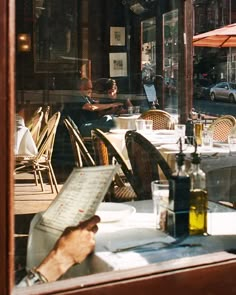 a person sitting at a table in front of a window with an open menu on it