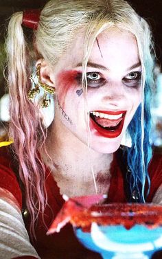 a woman with clown makeup holding a cake