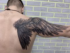 the back of a man's shoulder with black wings on it