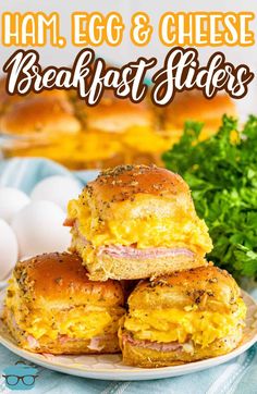 ham, egg and cheese breakfast sliders are stacked on a plate with parsley