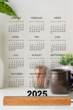 a desk with a calendar on the wall and a coffee cup in front of it