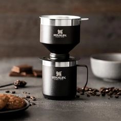 an espresso coffee maker sitting on top of a table next to some cookies