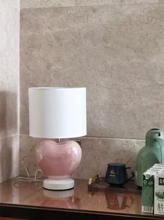 a pink lamp sitting on top of a wooden table next to a box of tissues