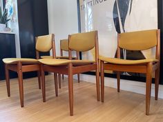 four chairs sitting on top of a hard wood floor next to a wall mounted poster