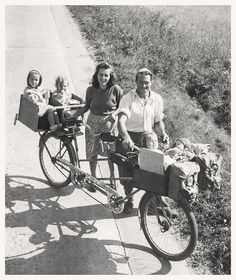 an old black and white photo of people on a bike with two children in the back