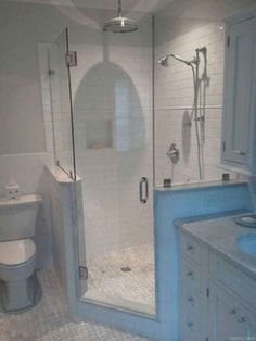 a bathroom with a walk in shower next to a white toilet and blue sink vanity