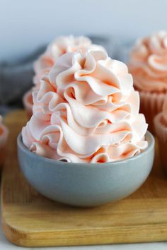 cupcakes with pink frosting in a bowl on a cutting board