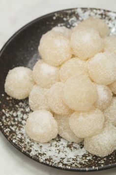 a black bowl filled with sugar covered donuts on top of a white countertop