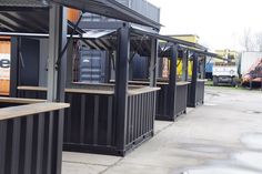 several black containers are lined up on the sidewalk