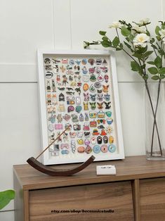 a vase filled with white flowers sitting next to a wooden dresser topped with stickers