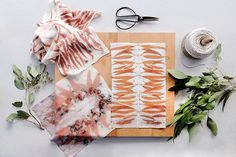 various items are laid out on top of a cutting board, including scissors and flowers