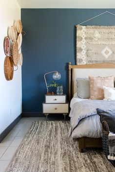 a bed room with a neatly made bed next to a wall mounted art on the wall