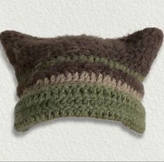 a crocheted pillow with a green and brown stripe on the front, sitting on a white surface