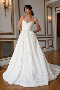 a woman in a white wedding dress posing for the camera with her hands on her hips