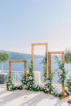 an outdoor ceremony setup with flowers and greenery on the ground, overlooking the water