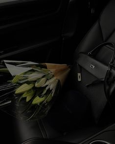 a bouquet of flowers sitting in the passenger seat of a car next to a purse