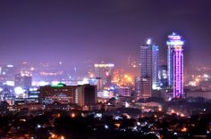 the city is lit up at night with bright lights in the buildings and skyscrapers