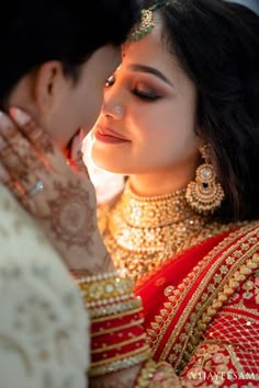 a woman in a red and gold outfit is kissing another woman's face with her hands