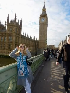 a woman is standing on a bridge in front of the big ben clock tower