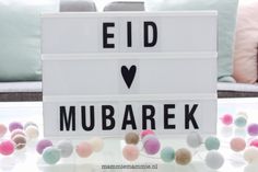 a sign that says eid mubaraek with pom - poms around it