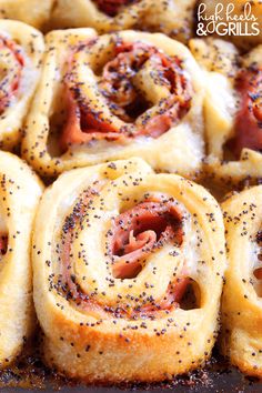 several rolls with meat and cheese in them on a baking sheet covered in poppy seed sprinkles