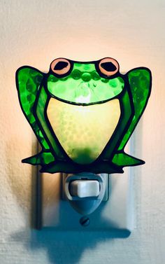 a green frog light sitting on top of a wall