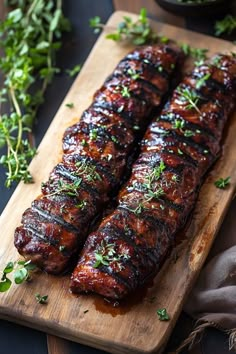 Two cooked pork ribs garnished with fresh herbs on a wooden cutting board. Pork Tenderloin For A Crowd Dinner Parties, Pork Tenderloin And Sour Kraut Recipes, Trader Joes Pork Tenderloin, Pork For Christmas Dinner, Rolled Pork Tenderloin Recipes, Blackened Pork Tenderloin, Broiled Pork Tenderloin, Deep Fried Pork Tenderloin, Boursin Stuffed Pork Tenderloin