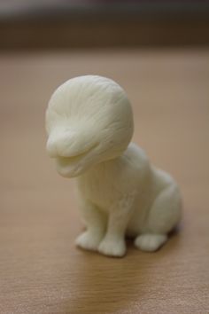 a small white animal sitting on top of a wooden table