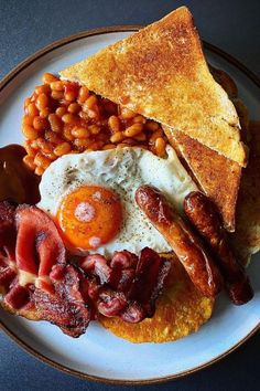 an english breakfast on a plate with bacon, beans and toast is pictured here in this image