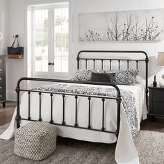 a bedroom with white walls and black metal bed frame