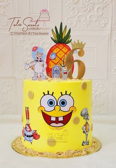 a yellow cake decorated with cartoon characters and pineapple